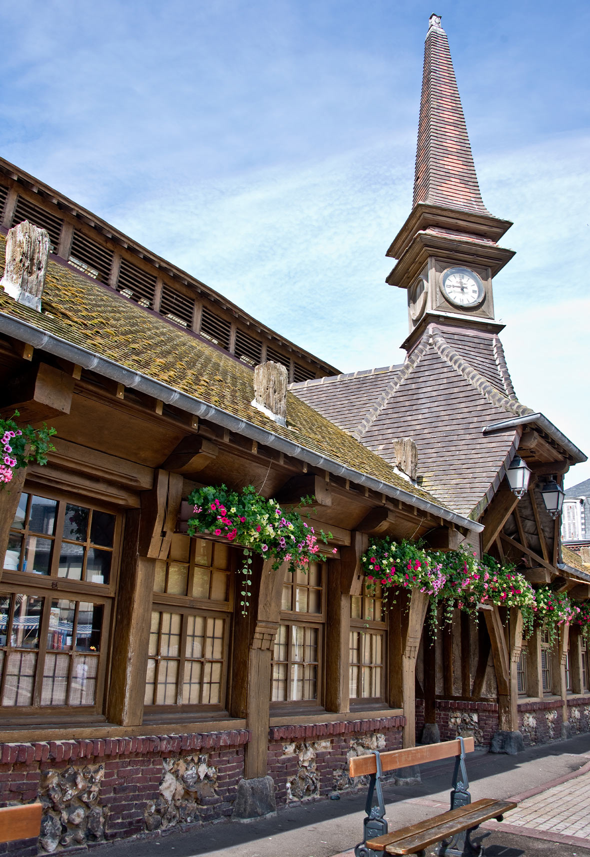 Old covered market building Etretat with clock tower and hanging floral baskets in the windows